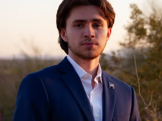 a man wearing a dark blue suit posed outside