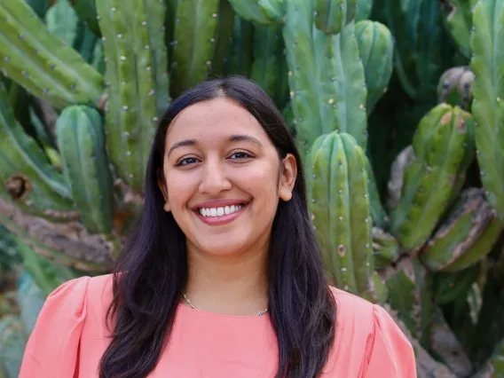 a smiling woman posed in front of a cactus