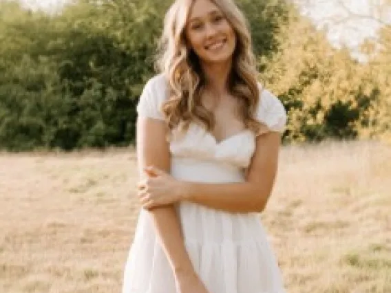 a woman wearing a white dress standing in a field